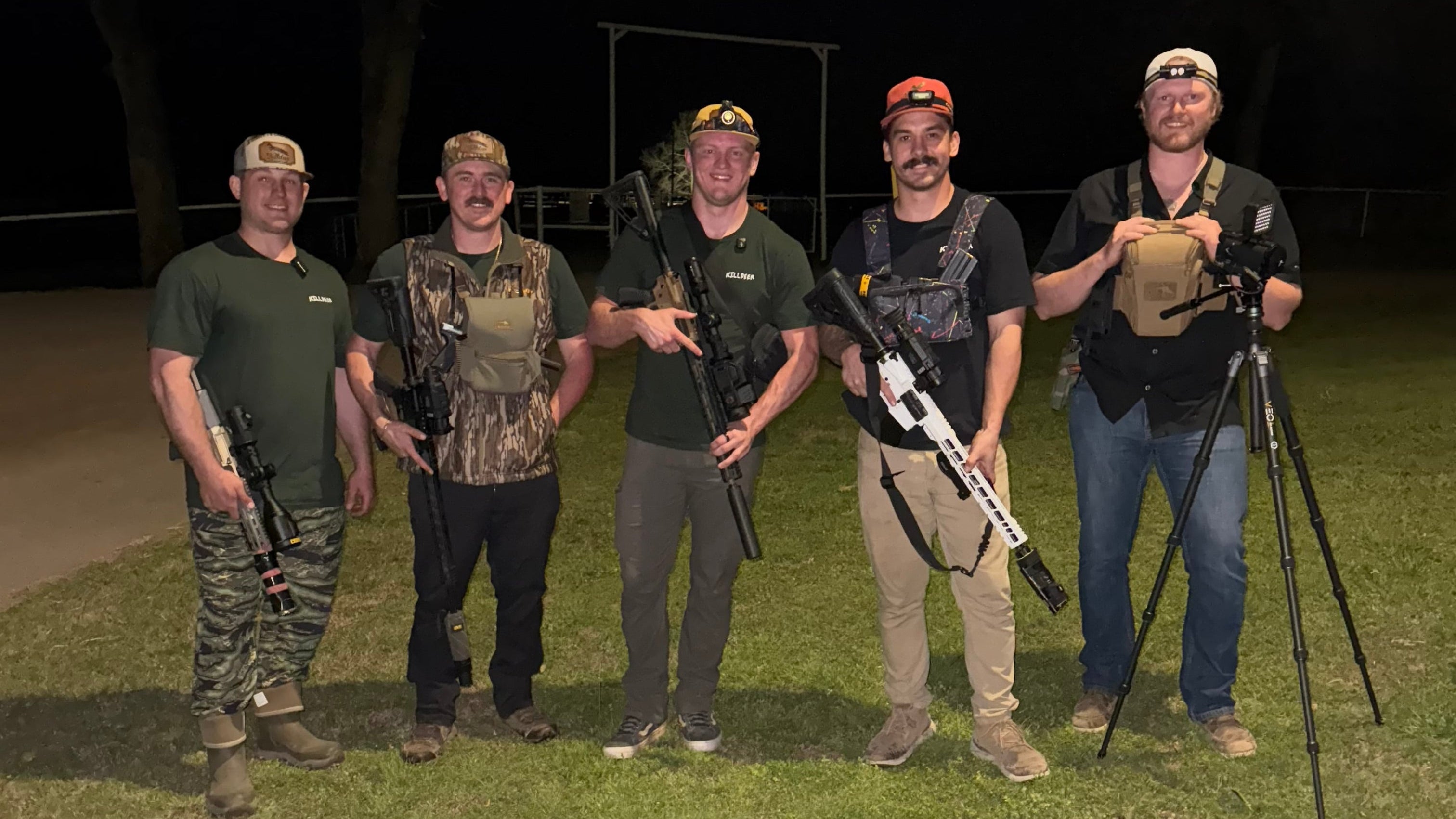 Group of people with rifles standing on a grassy field